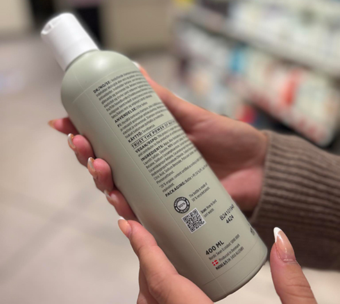 Kvinde tjekker ingredienslisten på en shampoo